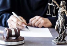 Judge Rules KSM Confession Was Involuntary Judge writing at desk with gavel and Lady Justice statue