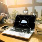 Laptop on desk showing cloud network icons