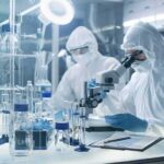 Scientists in protective suits using a microscope in a laboratory