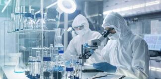 Scientists in protective suits using a microscope in a laboratory