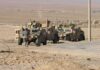 Soldiers near armored vehicles in a desert