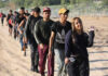 Line of people walking along a dirt path outdoors