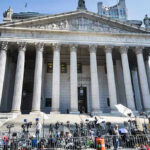 Reporters and photographers gathered outside a neoclassical courthouse