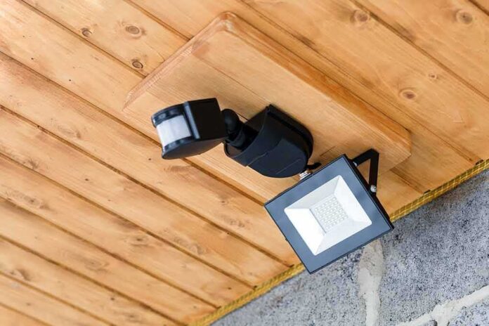 shutterstock_1065009536 Outdoor LED floodlight with motion sensor on wooden ceiling