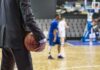 Basketball coach in suit holding ball courtside
