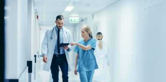 Doctors walking in a hospital corridor reviewing a tablet