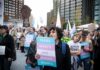 Crowd of protesters holding trans rights signs at a city rally