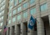U.S. government building facade with American and blue departmental flags
