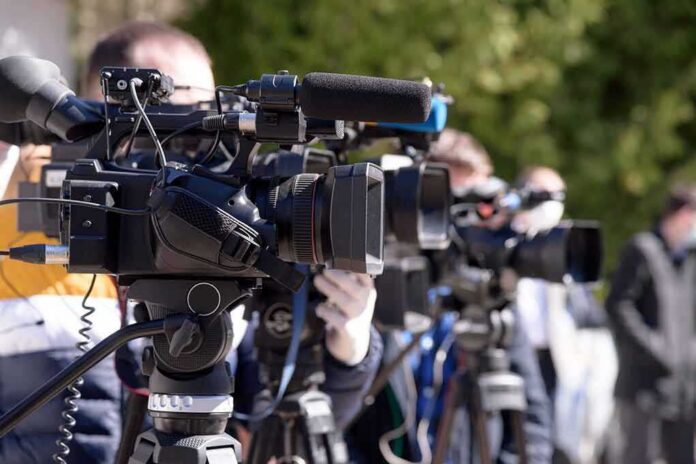 shutterstock_1701104950 Video cameras on tripods at an outdoor press event