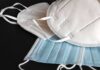 Face masks including white KN95 and blue surgical types on a dark surface