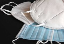 Face masks including white KN95 and blue surgical types on a dark surface