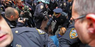 Police officers detain a person amid a crowded street scene