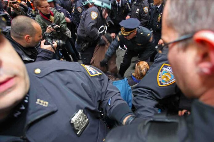 Police officers detain a person amid a crowded street scene
