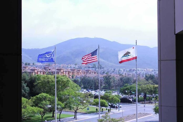 three flags waving in front of suburban neighborhood and mountains