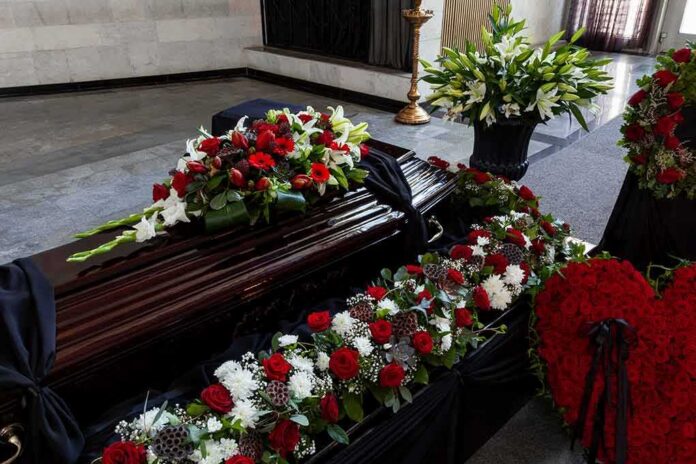shutterstock_1869583603-1 Coffin with floral arrangements at a funeral service