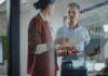 Robotics Startup Lands AI Leader Two colleagues discussing documents in a glass-walled office
