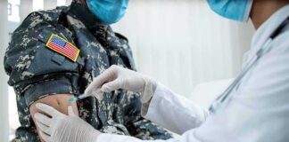 Healthcare worker giving vaccine to person in military uniform