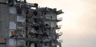 Partially collapsed apartment building with exposed rooms and debris