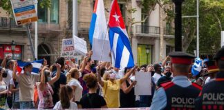 Walter Jones amid crowd at street protest with Cuban flags and police present