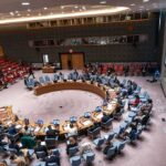 Germany Expands Deportations With Taliban Help Delegates seated around a circular conference table in a large chamber