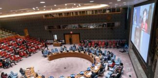 Delegates seated around a circular conference table in a large chamber