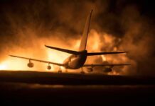 Airplane on runway with large fire and smoke at night