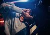 Police officer handcuffing person at night by patrol car
