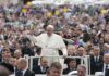 Francis waves from a vehicle amid a large crowd; Keith Allen and Andreas Hestler are also present