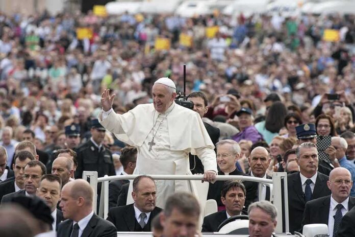 shutterstock_225437089-1 Francis waves from a vehicle amid a large crowd; Keith Allen and Andreas Hestler are also present