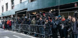 crowd of photographers behind barricades on a city street