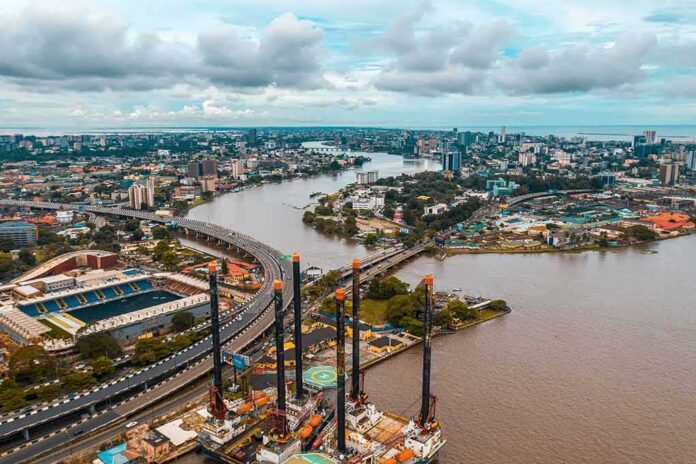 shutterstock_2314211431-1 Aerial view of a river cutting through a modern city with bridges and ports