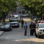 Two Suspects Arrested in Fatal Attack on Musician’s Family Police officers secure a residential street with patrol cars and yellow tape