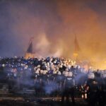 Riot police gather amid smoke at night