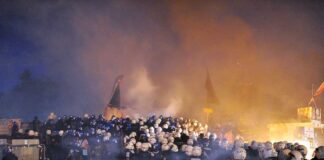 Riot police gather amid smoke at night