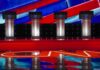 Debate stage with four empty podiums and bright red and blue backdrop