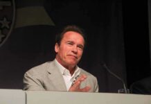 Arnold Schwarzenegger speaking at a podium with a microphone