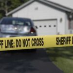 Sheriff line tape blocking a suburban driveway