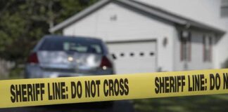 Sheriff line tape blocking a suburban driveway
