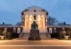Statue before a neoclassical rotunda at dusk