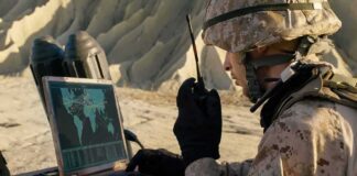 soldier using a rugged laptop and radio in a desert setting