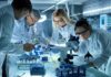 Scientists collaborating in a laboratory around a microscope