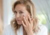 BBC Pulls Bare-Nails Article After Backlash woman touching her cheek while looking in a mirror