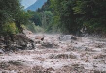 Nepal Flood Destroys 35 Homes and Bridges Flooded river gorge with fast muddy water and rocks