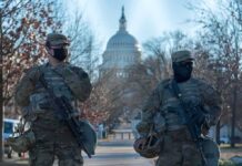 Two armed soldiers stand guard near a domed government building