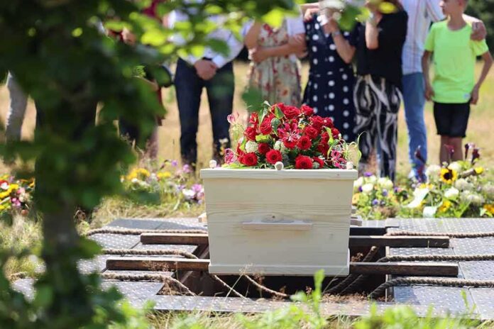 White coffin with red flowers at outdoor burial