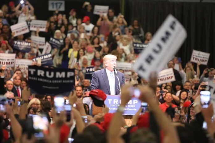 Donald Trump speaks at a rally podium as a large crowd cheers; Orel Hershiser, Ion Marin, and Billy Joe DuPree present