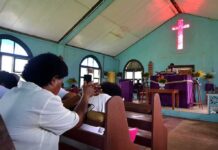 Crucifix Falls During Live-Streamed Mass Congregation inside a church with a speaker at the pulpit